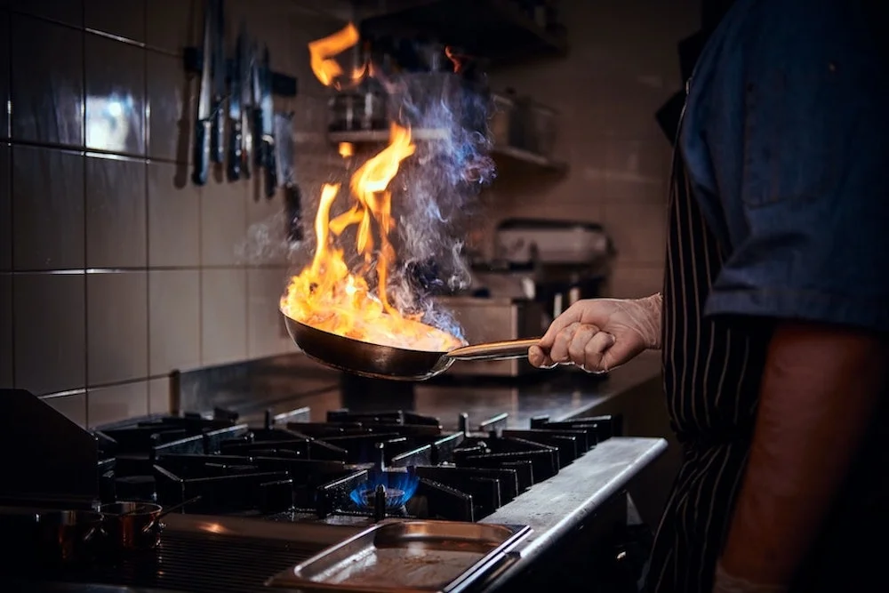 Mann mit Pfanne in der Hand am kochen